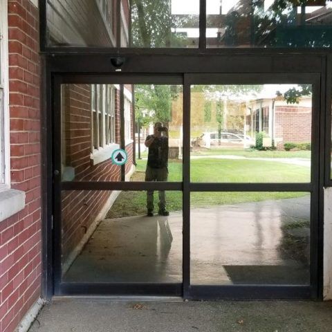 Automatic Doors Installation and Repair - A man taking a picture of himself in a sliding glass door