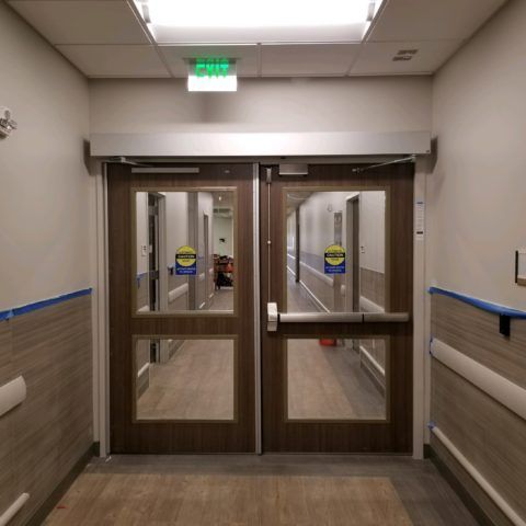 A hallway with two doors and a green exit sign