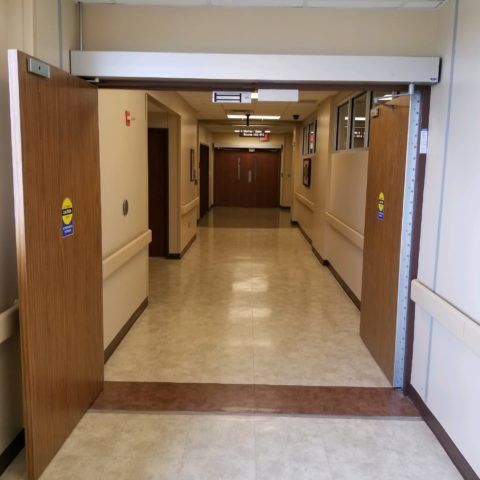 Automatic Doors Installation and Repair - A hospital hallway with a door that says ' emergency exit ' on it