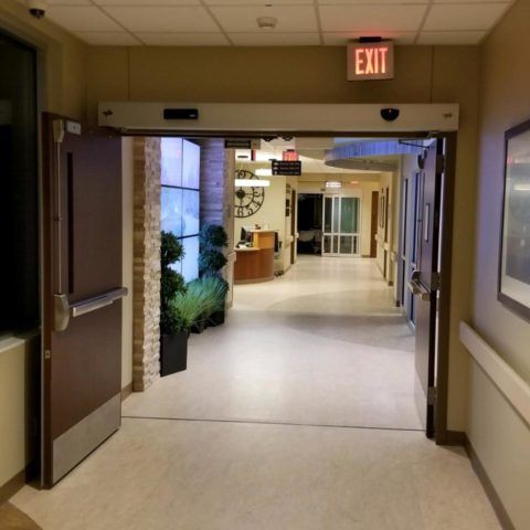 A hospital hallway with an exit sign above the door