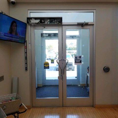 Automatic Doors Installation and Repair - A waiting room with two glass doors and a tv on the wall