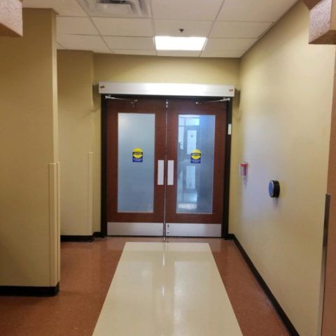 Automatic Doors Installation and Repair - A hallway with a glass door and a sticker on the door that says ' emergency exit '