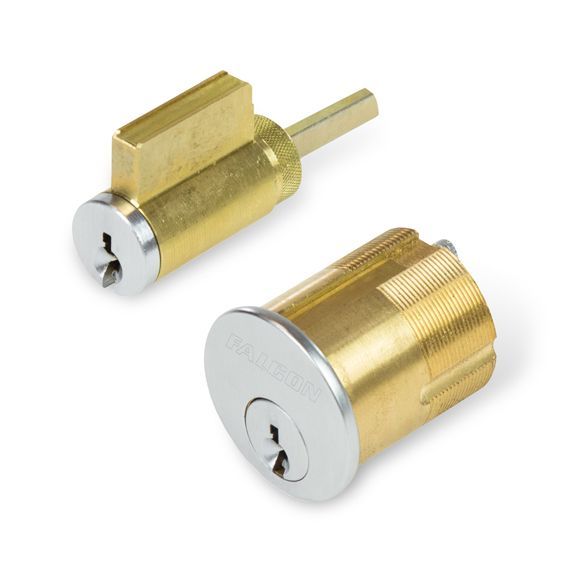 Two brass cylinders with a key in them on a white background