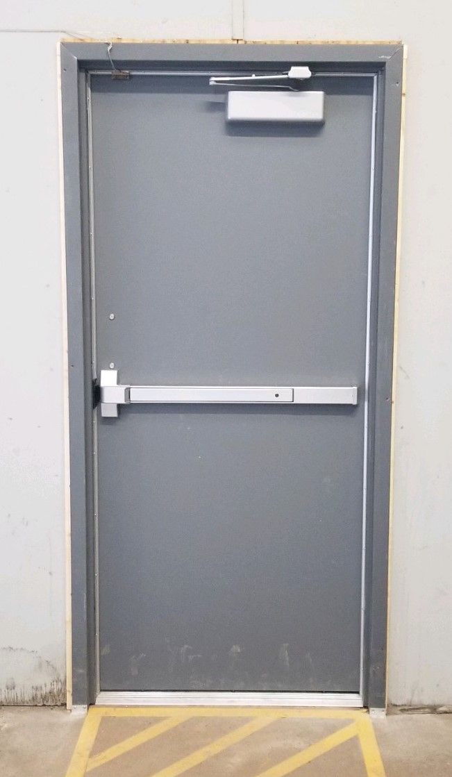 Hollow Metal Doors Installation and Repair - A gray door with a panic bar on it is in a building.