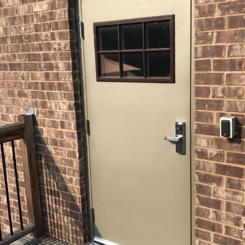 Hollow Metal Doors Installation and Repair - A door with a small window on the side of a brick building