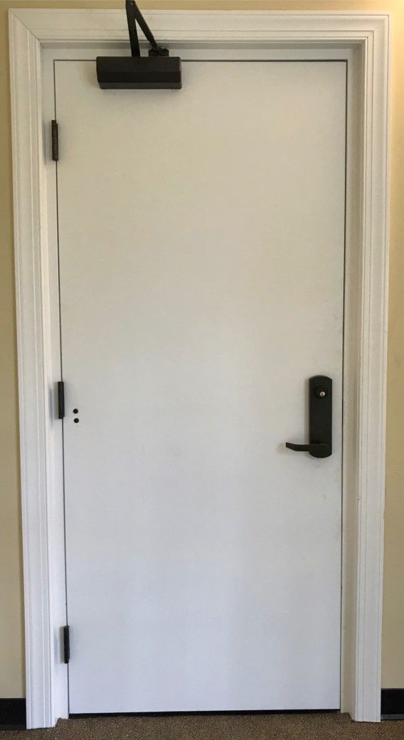 A white door with a black handle is in a room.