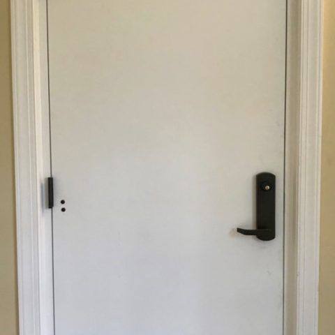 Hollow Metal Doors Installation and Repair - A white door with a black handle is in a room.