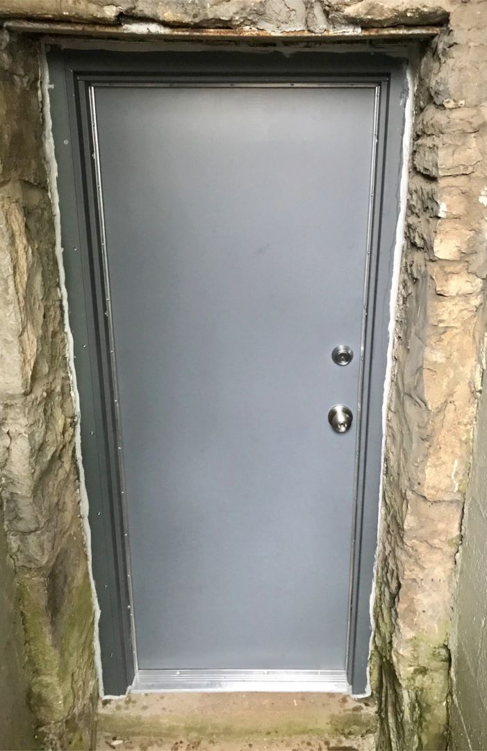 Hollow Metal Doors Installation and Repair - A metal door is sitting on top of a stone wall.