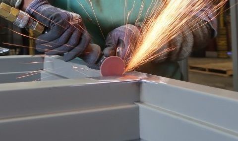 Hollow Metal Doors Installation and Repair - A person is grinding a piece of metal with sparks coming out of it.
