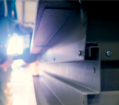 Hollow Metal Doors Installation and Repair - A close up of a metal beam with a person welding in the background.