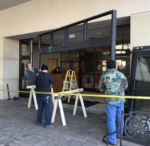 A group of people are working on a door outside of a building.