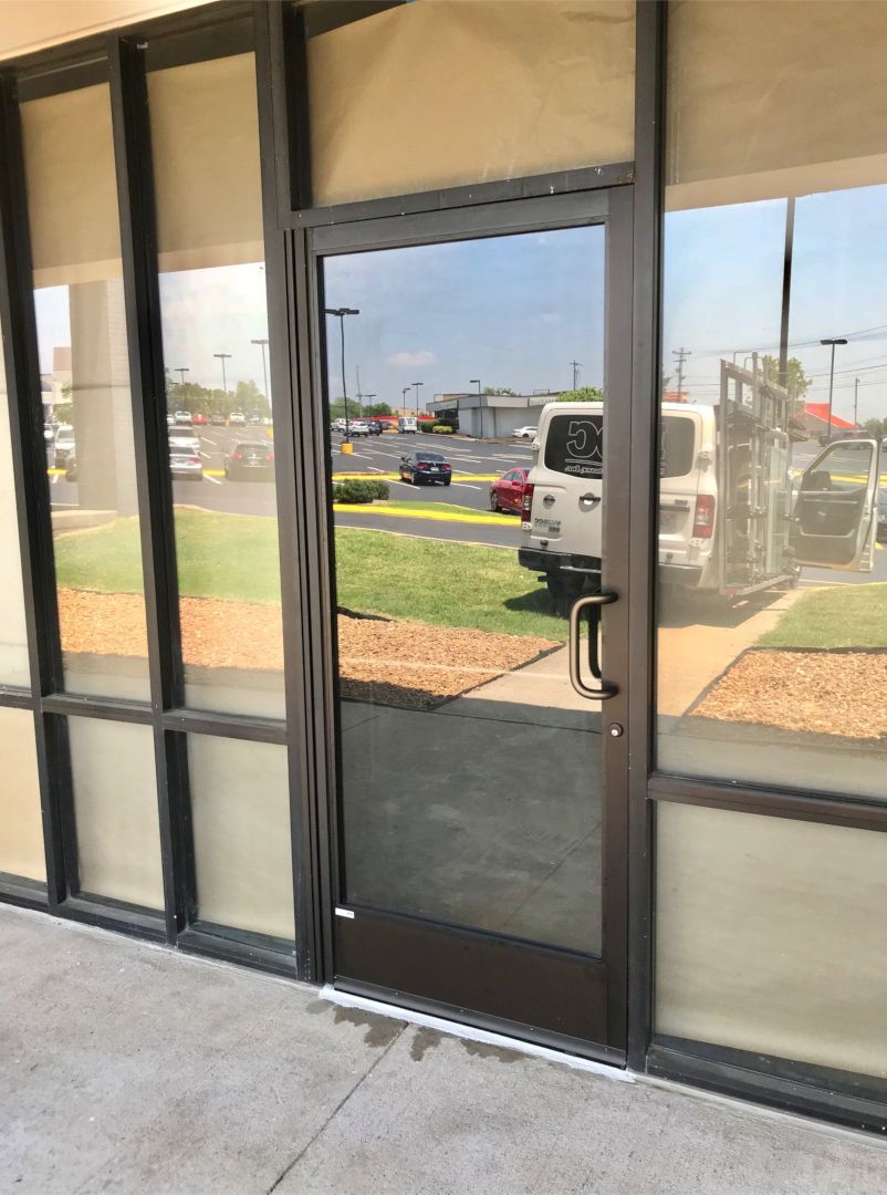 Storefronts & Glass Doors Installation and Repair - A door with a reflection of a white van in it.
