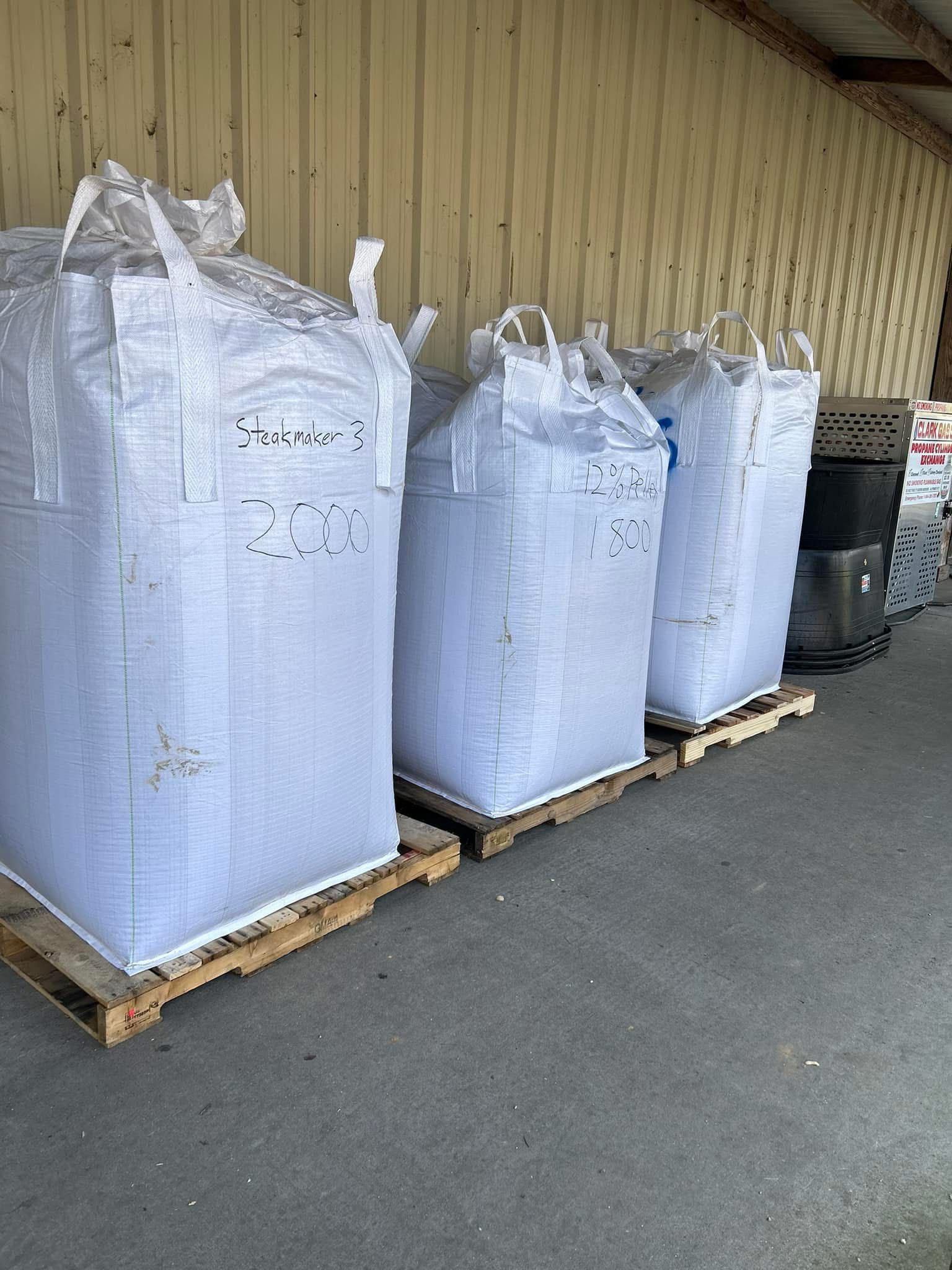 A row of white bags sitting on top of wooden pallets.