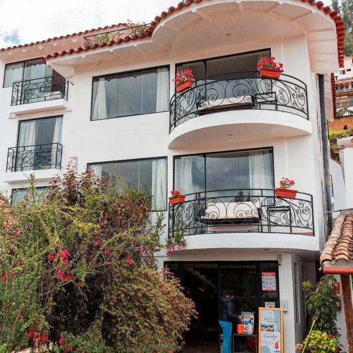 Edificio de apartamentos blanco de varias plantas con balcones y macetas rojas, visto desde la calle.