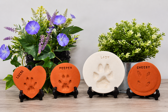 Four pet paw-print plaques on stands, flanked by purple and green flower arrangements.