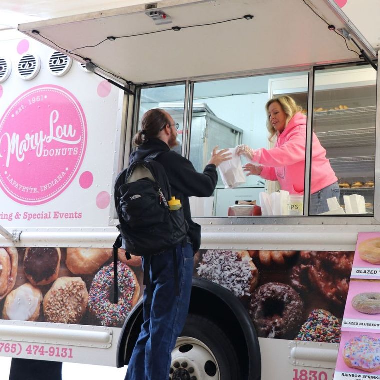 Woman handing bag of donuts to man