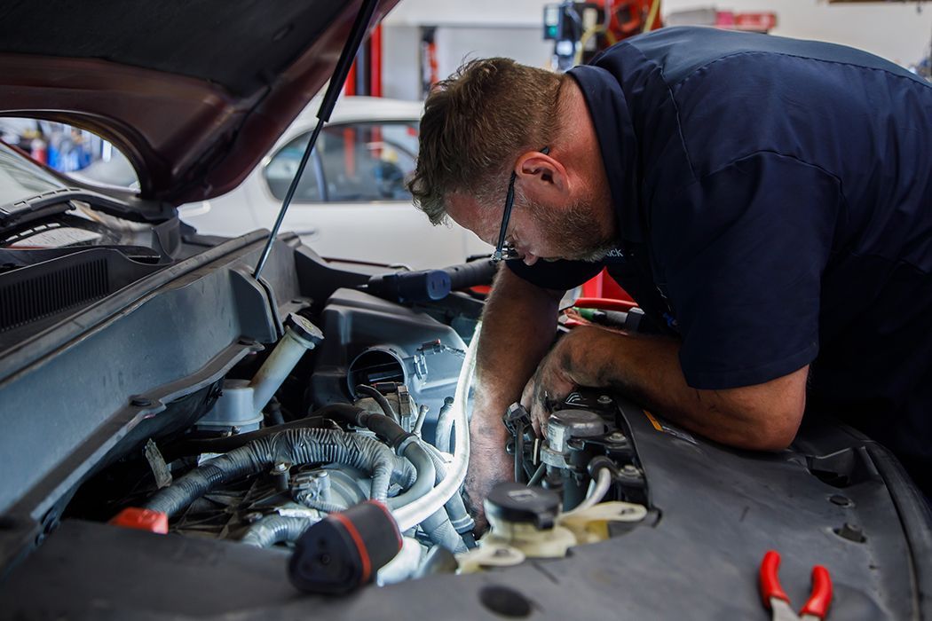 Our expert technician repairing a vehicle under the hood in our garage in Centerville, UT | Baker Automotive