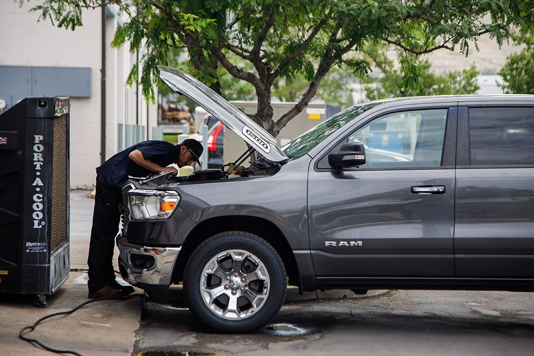 Expert technician at work outside of our shop, under hood of black truck in Centerville, UT | Baker Automotive