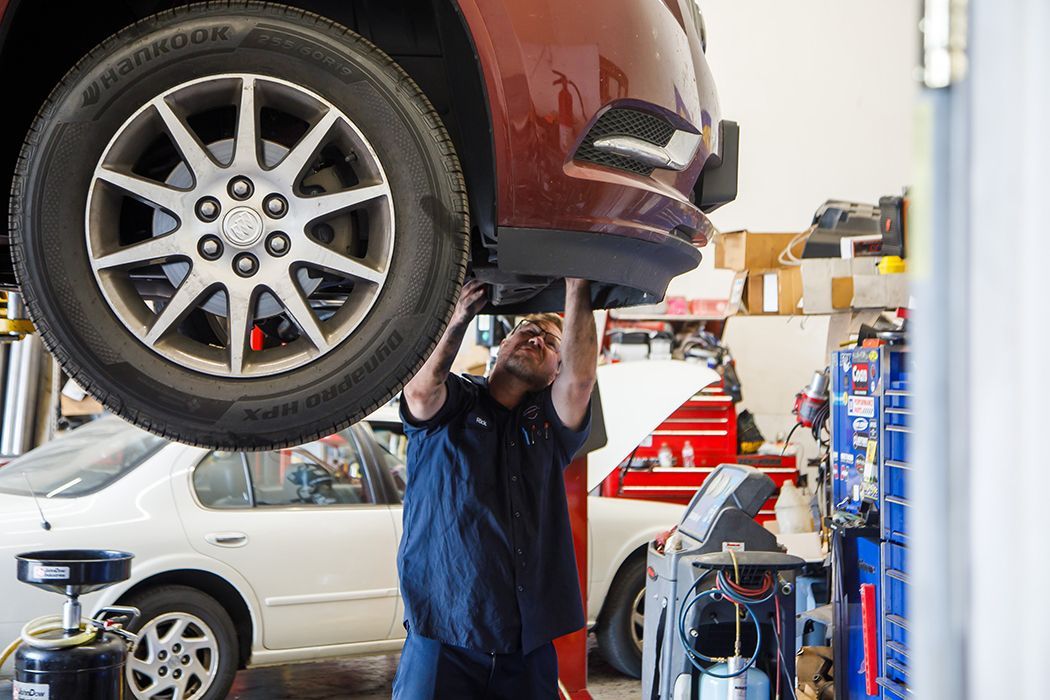 Our expert technician repairing an elevated vehicle in our garage in Centerville, UT | Baker Automotive