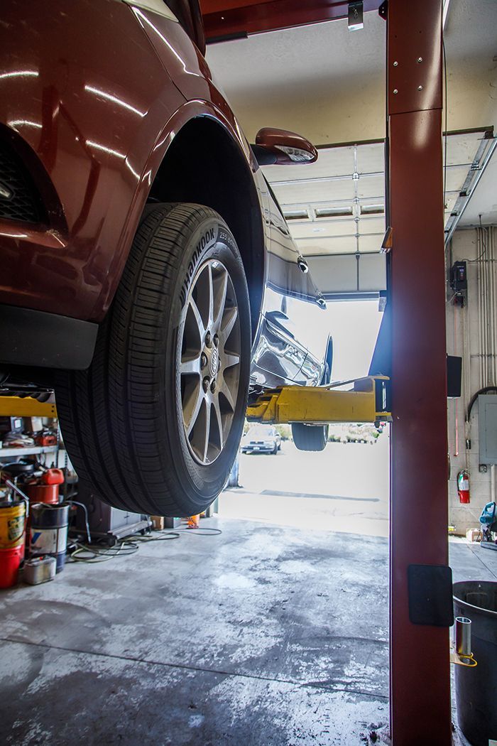 Lifted up red car in our garage in Centerville, UT | Baker Automotive