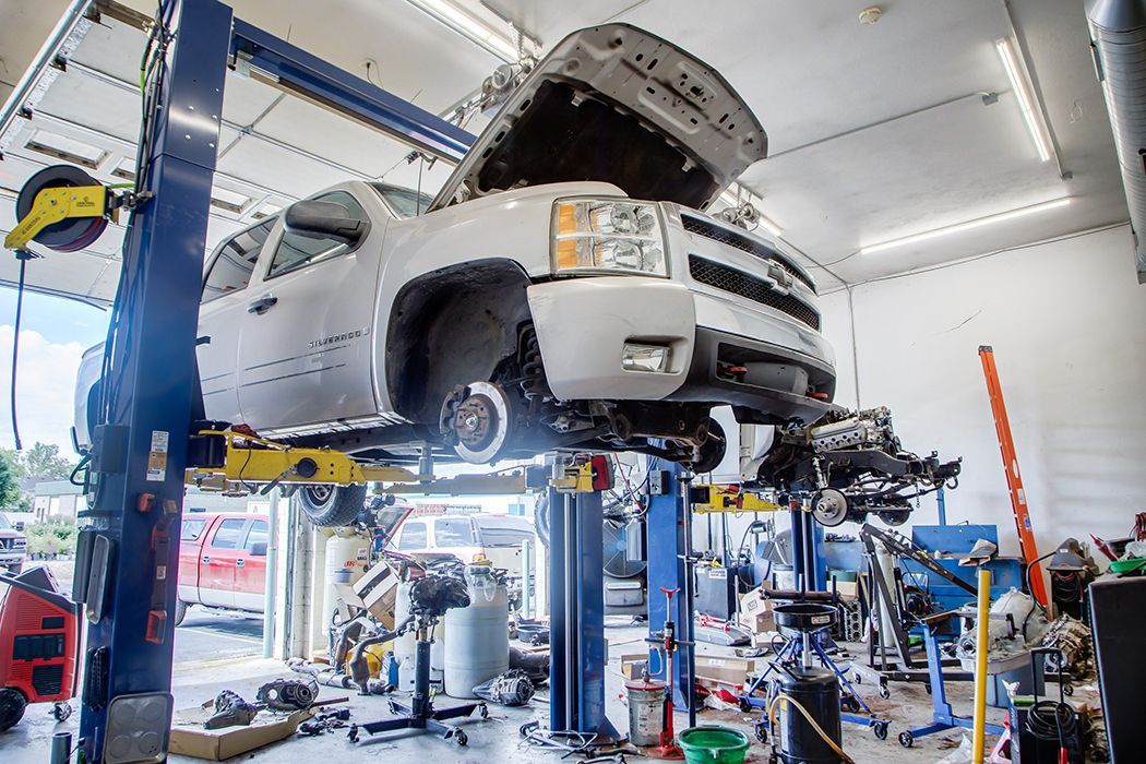 White truck lifted up in the middle of repairs in our garage in Centerville, UT | Baker Automotive