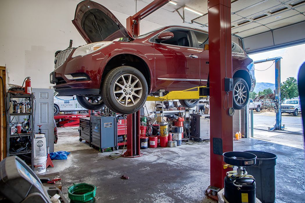 Lifted up red SUV in our garage in Centerville, UT | Baker Automotive