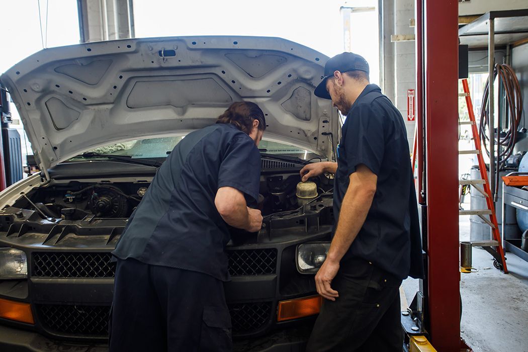 Two of our expert technicians working under the hood of a vehicle in our garage in Centerville, UT | Baker Automotive
