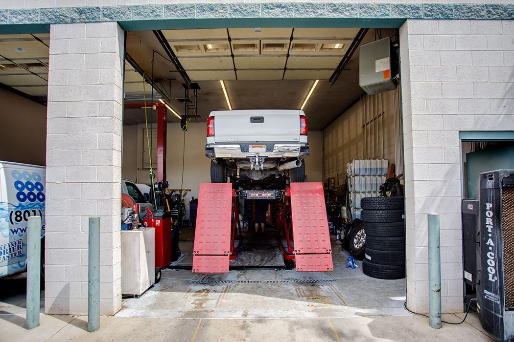 White truck lifted up in our garage in Centerville, UT | Baker Automotive