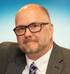 A bald man with a beard and glasses is wearing a suit and tie.