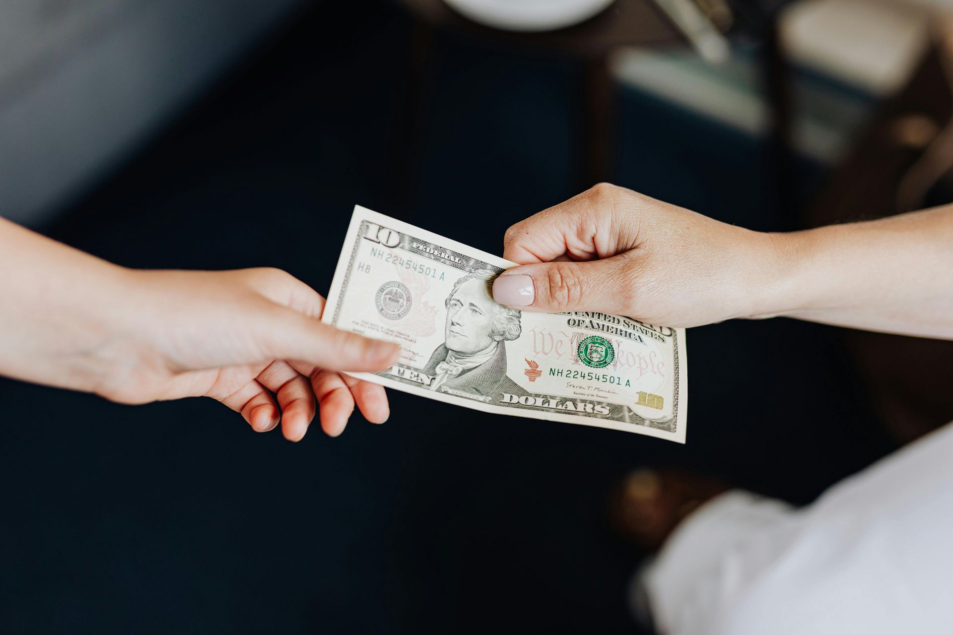 Hands exchanging a $100 bill, with one hand accepting it.
