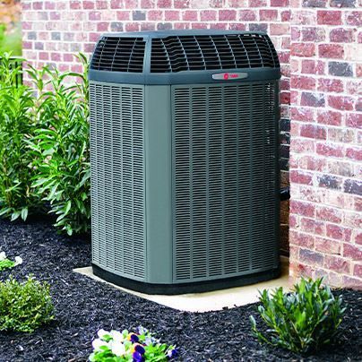 A large air conditioner is sitting on the side of a brick building.