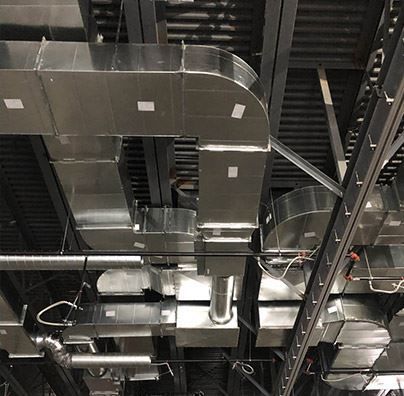 A bunch of stainless steel pipes are hanging from the ceiling of a building.