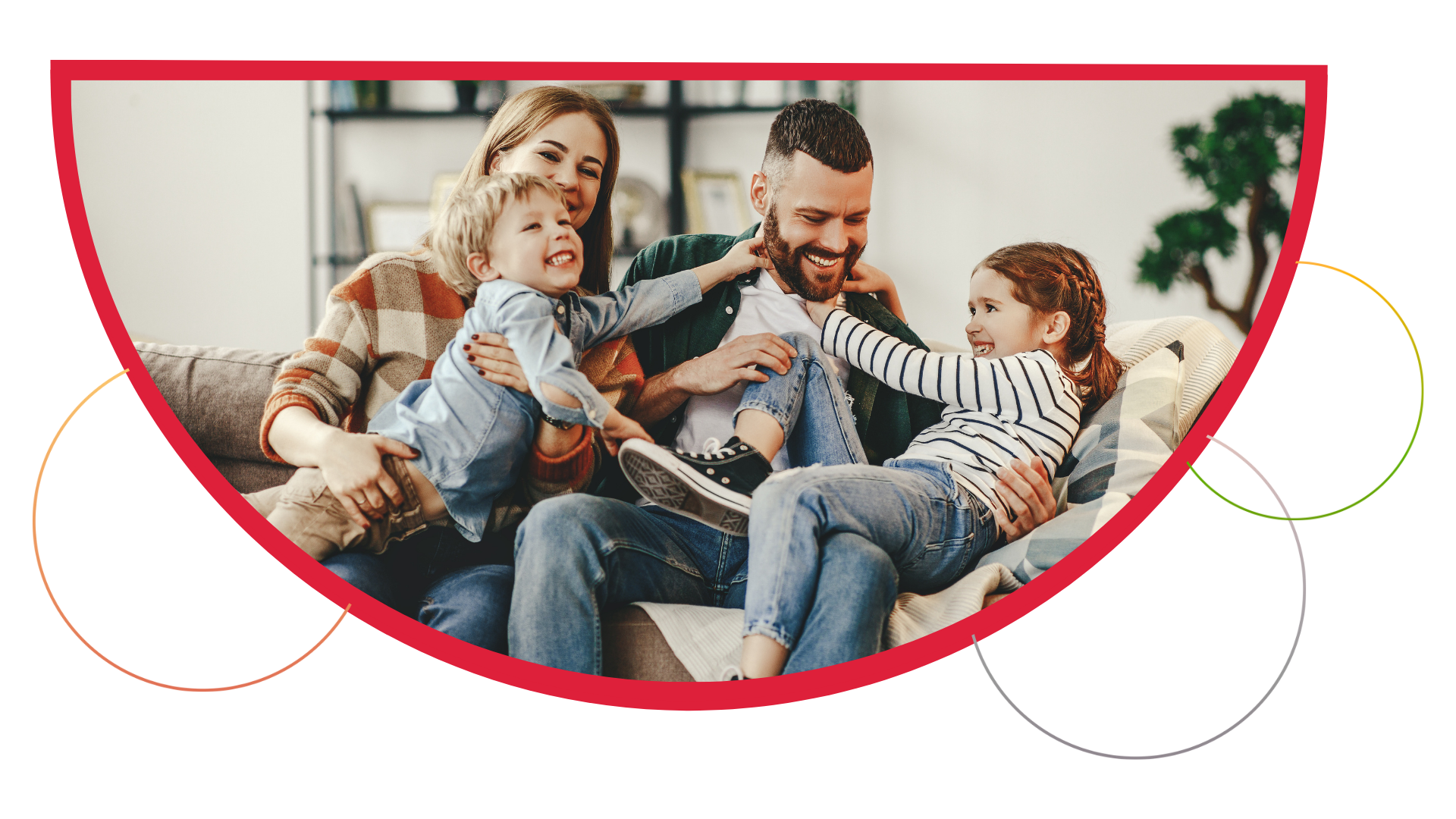 Family of four laughing together on a couch.