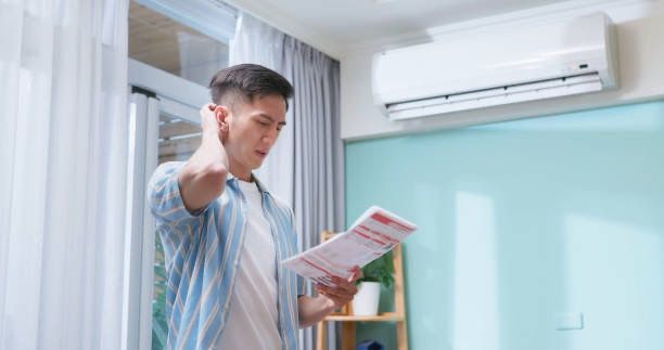 high electric bill stressing out man looking at it