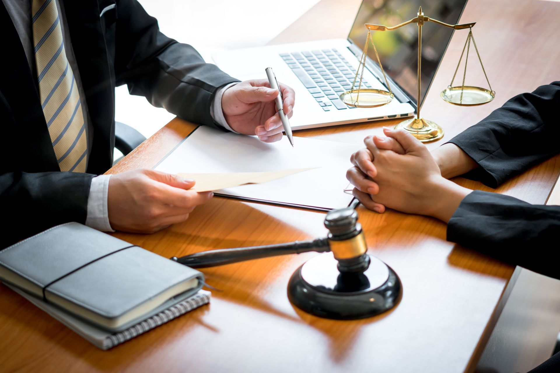 Lawyers discussing documents at a desk with a gavel and laptop in a meeting room