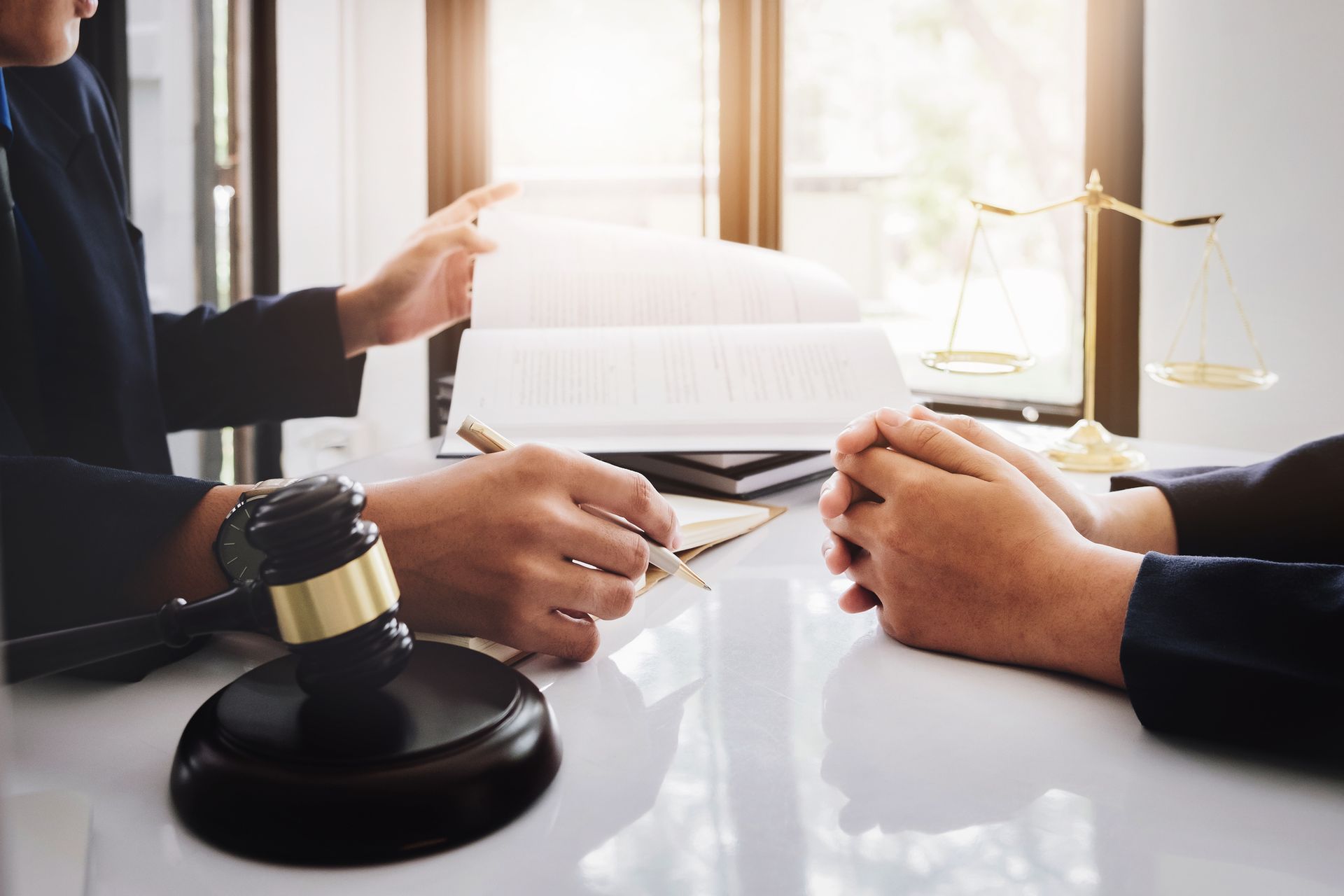 Lawyer reviewing documents with a client, gavel, scales of justice, window.