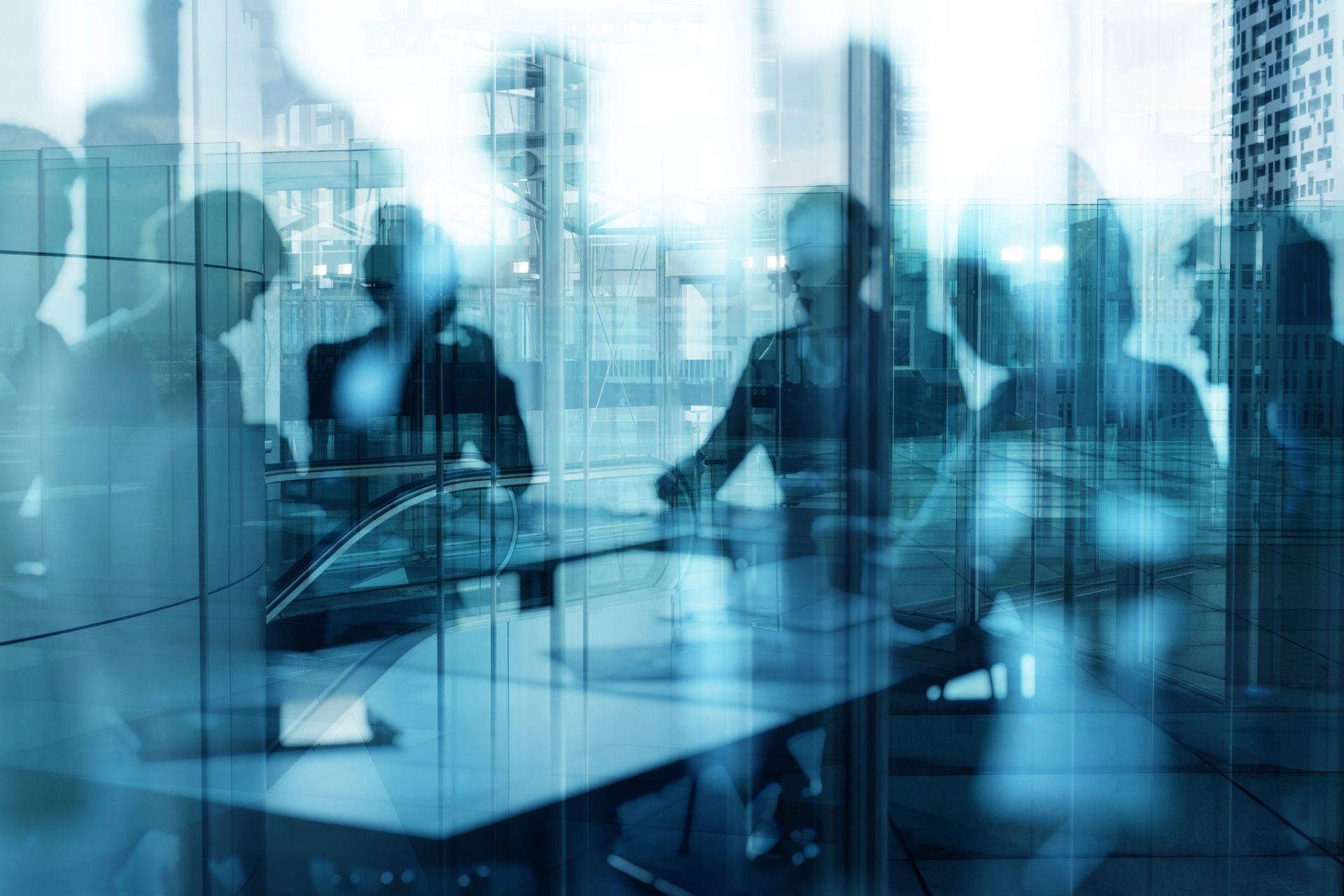 Businesspeople at a table in a meeting, overlaid with a city skyline, muted blue tones.