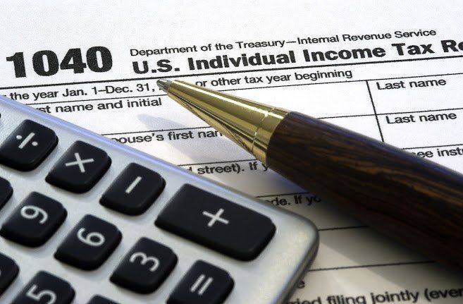 Tax form 1040, calculator, and pen on a table, ready for tax preparation.
