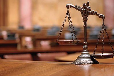 Scales of justice on a wooden table in a courtroom.