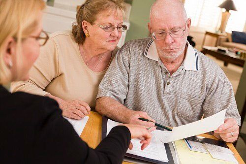 A financial advisor reviewing documents with an elderly couple at a table.