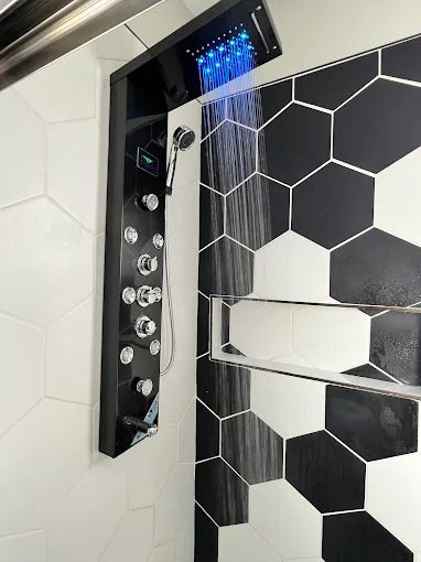 Gold kitchen faucet with black coil against white subway tile backsplash.