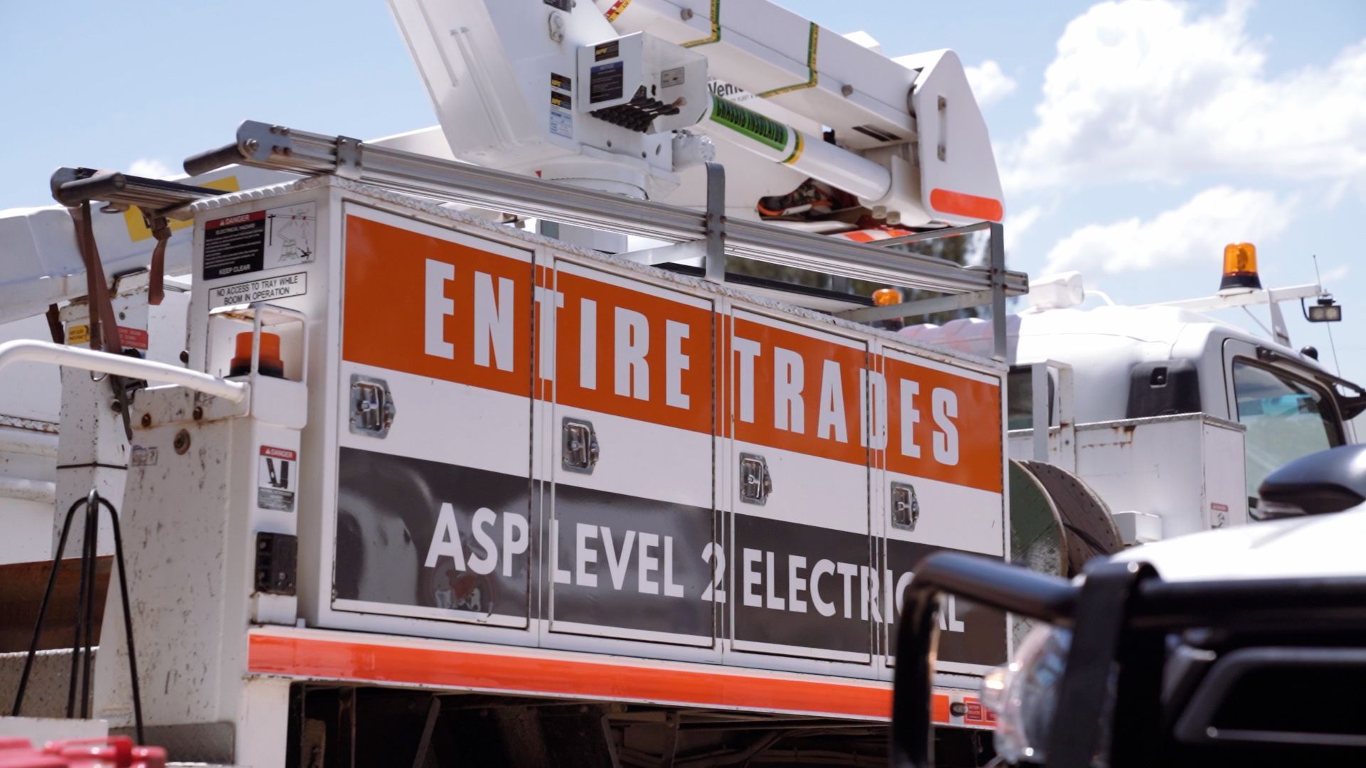 White service truck parked at a loading dock beside a building, with company logos on the side.