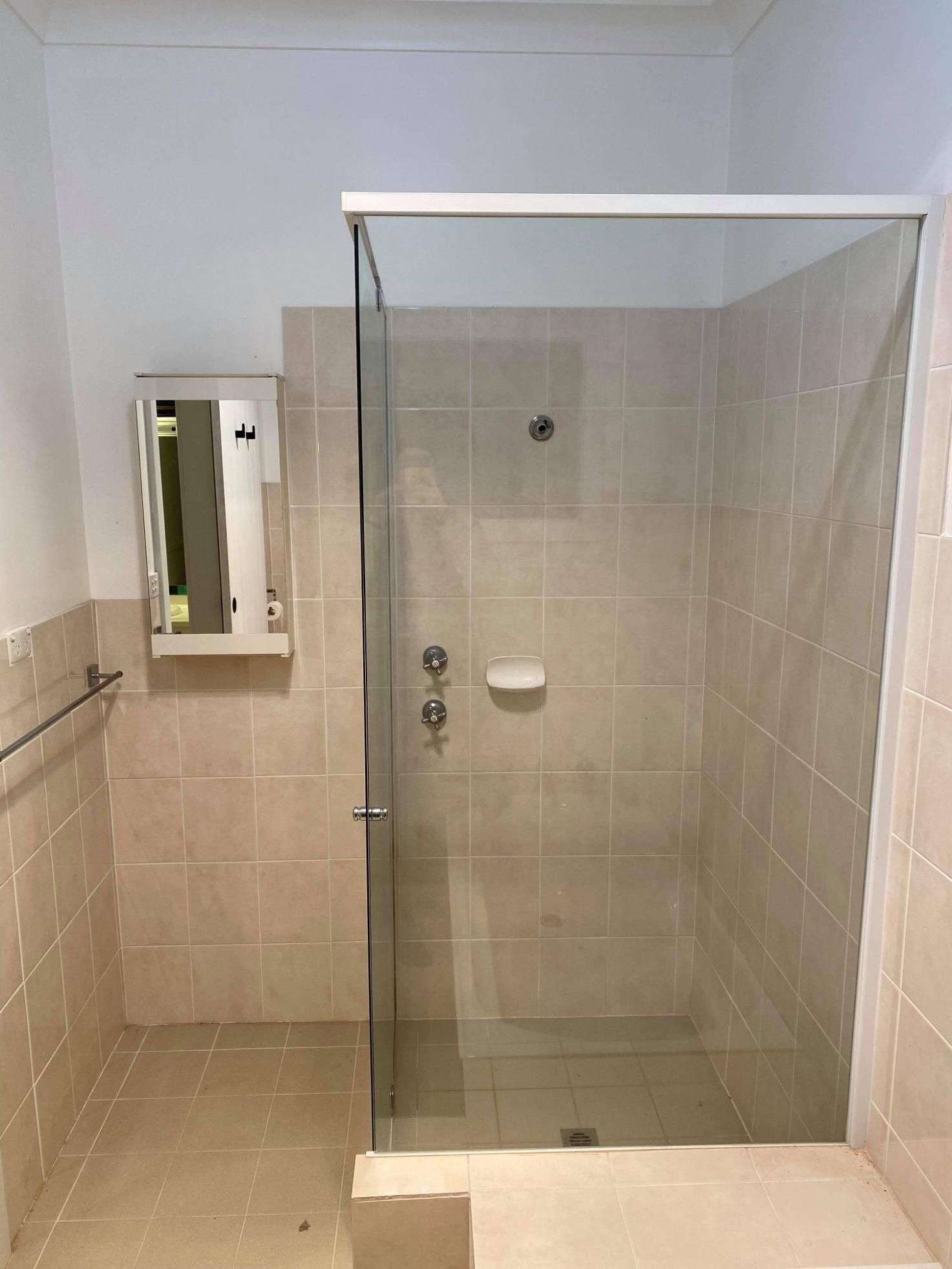 Small tiled bathroom with a glass shower stall and a wall-mounted cabinet.