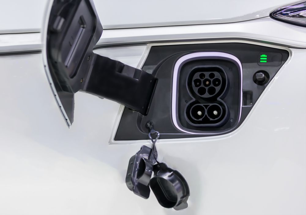 Open EV charging port on a white car with charging cable connected