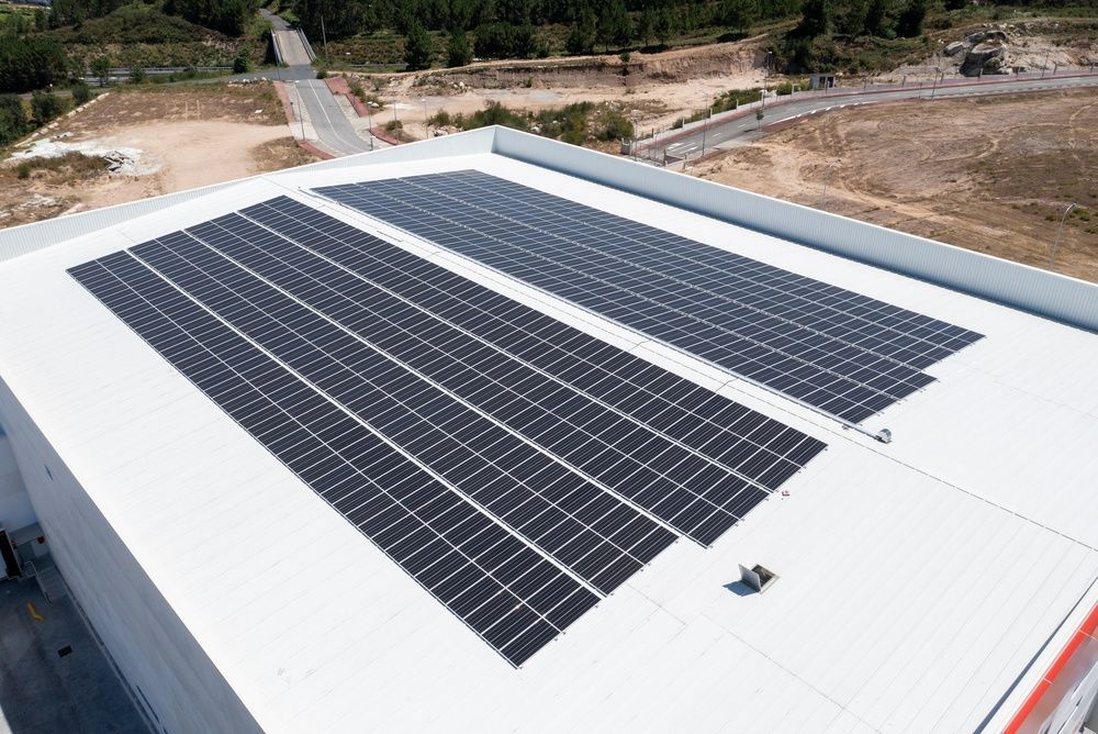 Workers installing solar panels on a rooftop with a ladder against a brick wall.