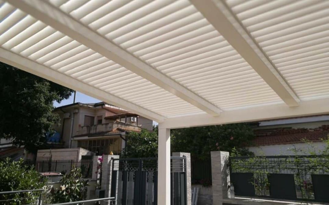 Tettoia con persiane beige e vista sugli edifici e sul verde.
