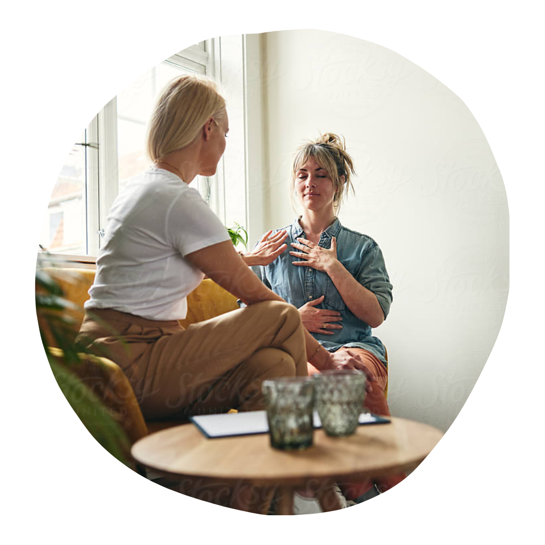 Two people talking on a sofa beside a round table with candles in a bright living room