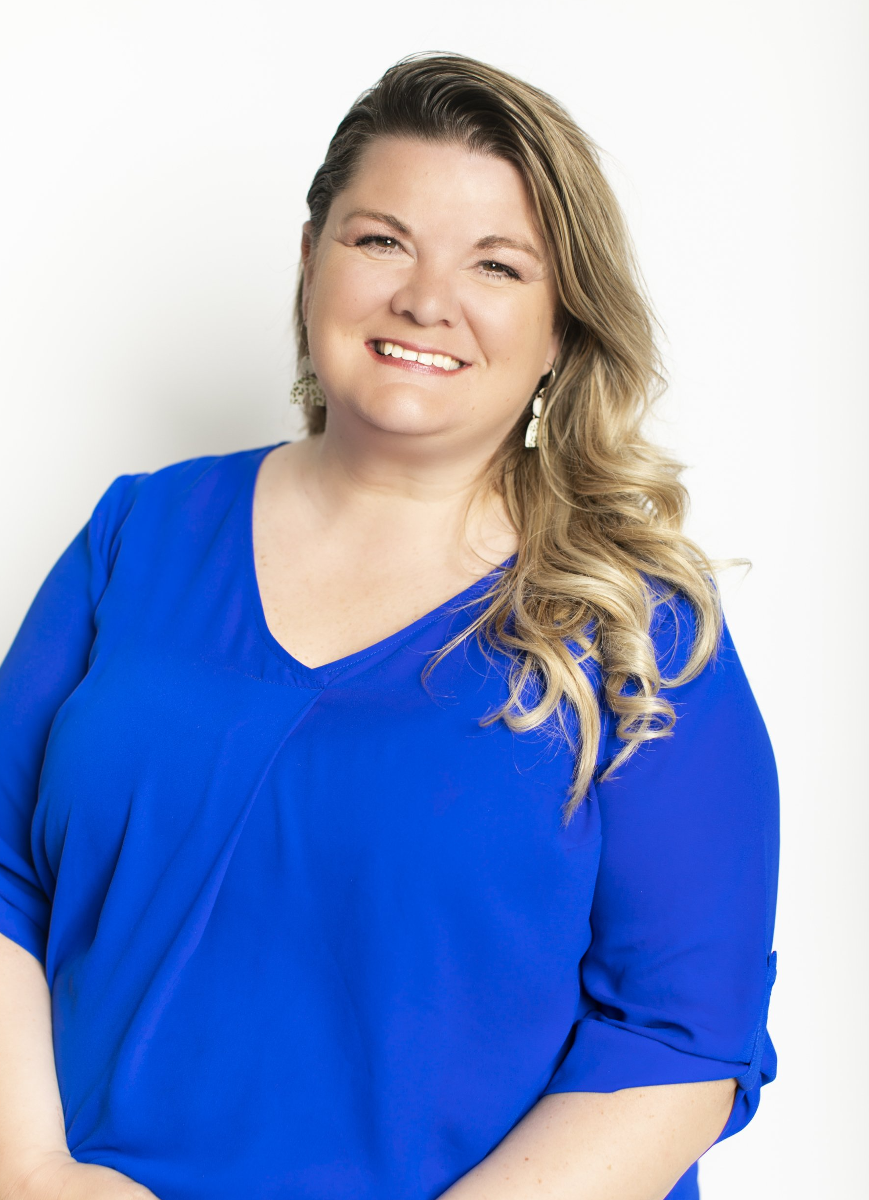 Smiling person in a bright blue blouse against a white background