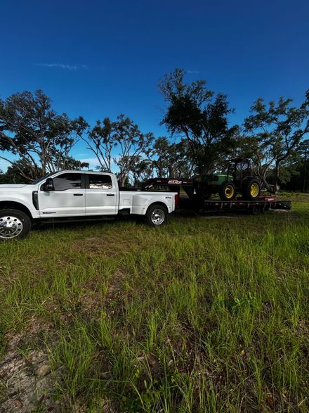 White pickup truck parked in a grassy field beside trees under a blue evening sky