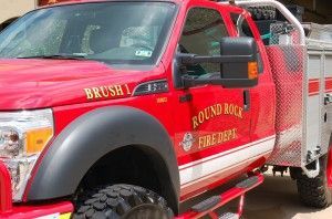 A red truck from the Round Rock fire department is parked in a garage.